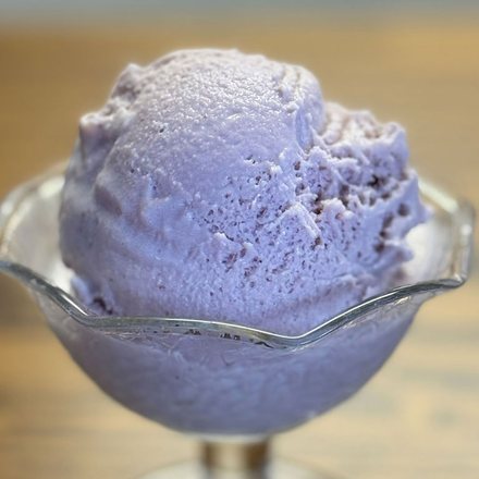 A scoop of homemade black raspberry ice cream in a footed glass dish