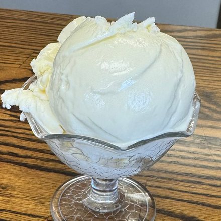 A scoop of homemade lemon ice cream in a footed glass dish