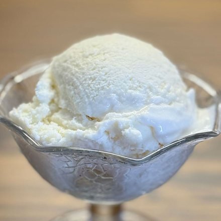 A scoop of homemade vanilla ice cream in a footed glass dish